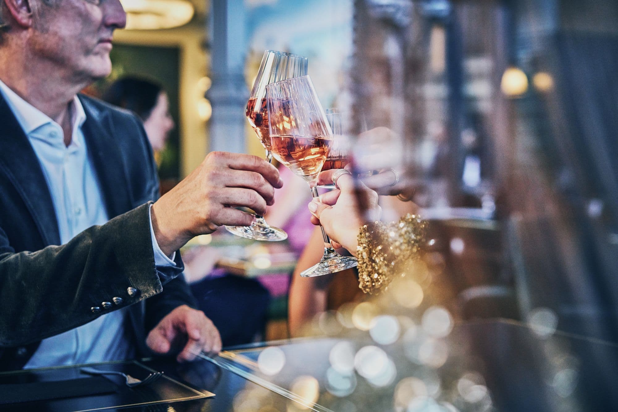 HADLEY-Teammitglieder stoßen mit Gläsern Roséwein in eleganter Bar-Atmosphäre an.