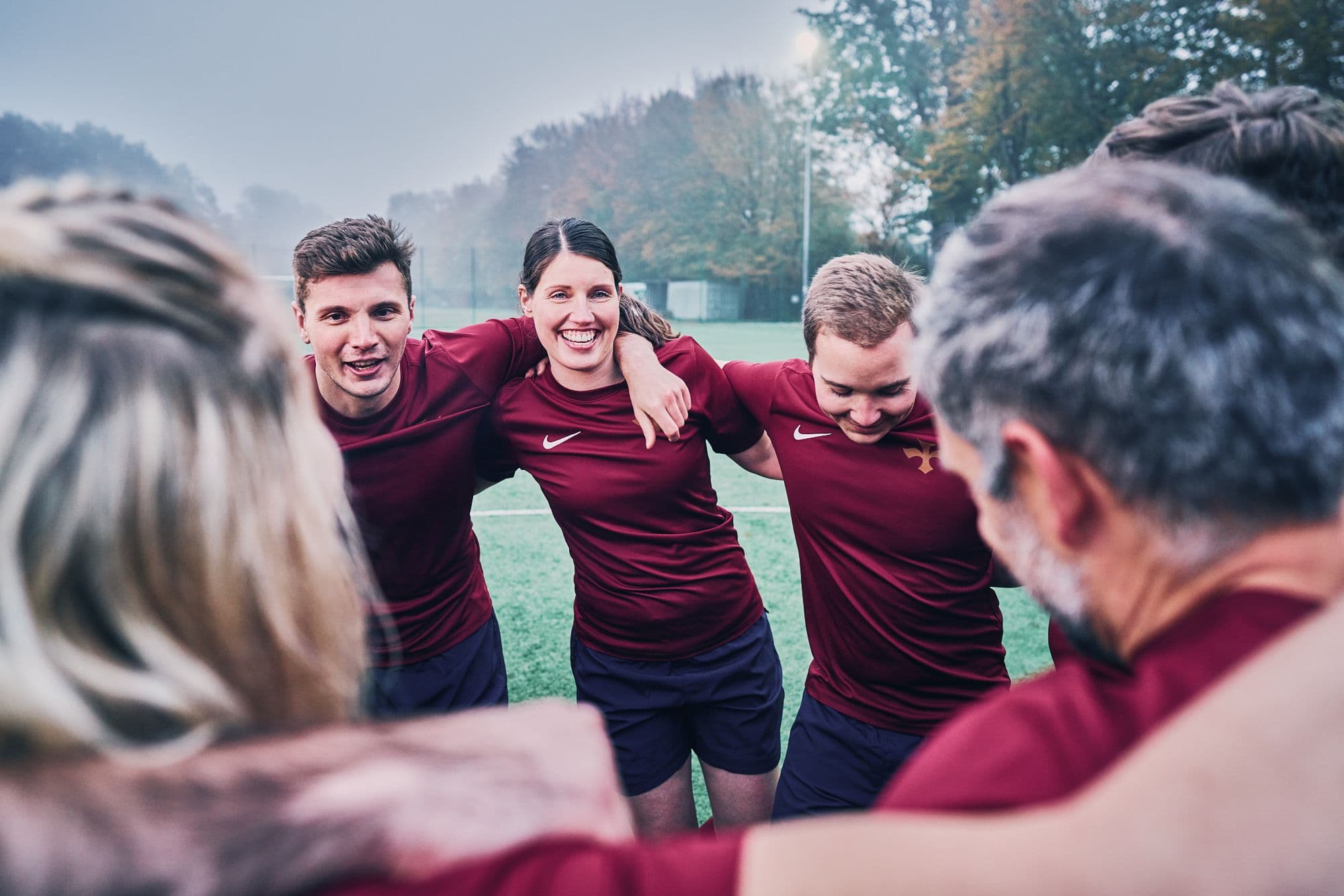 HADLEY-Teammitglieder in Rugby-Trikots stehen im Kreis, legen die Arme umeinander und blicken motiviert in die Runde.